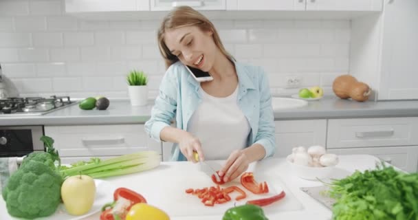 Vrouw in gesprek op smartphone in de keuken — Stockvideo