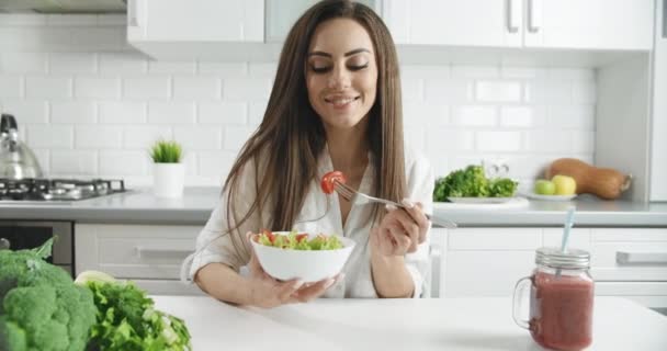Женщина наслаждается салатом на кухне — стоковое видео