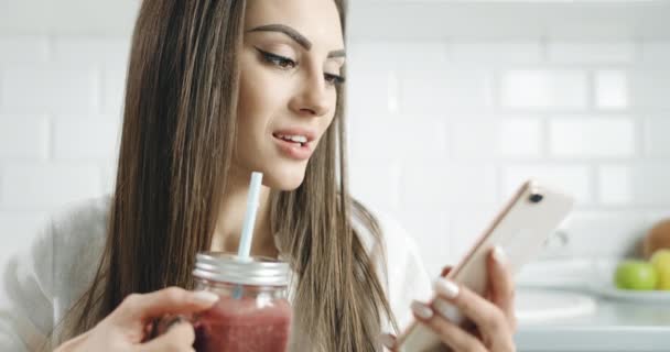 Mujer Bebiendo Smoothie y Desplazamiento Smartphone — Vídeos de Stock