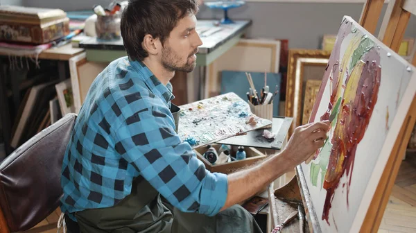 Pintor masculino concentrado usando uma faca de paleta — Fotografia de Stock