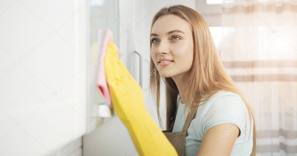 Concentrated Young Woman Thoroughly Cleaning Kitchen Furniture