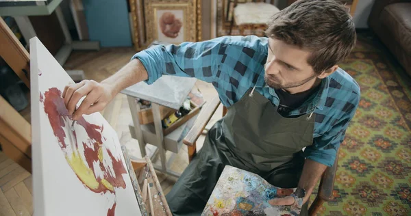 Pintor masculino joven concentrado haciendo un trazo preciso de pintura —  Fotos de Stock