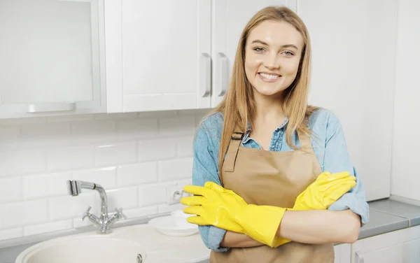 Lindo servicio de limpieza rubia en guantes posando en la cocina Fotos de stock libres de derechos