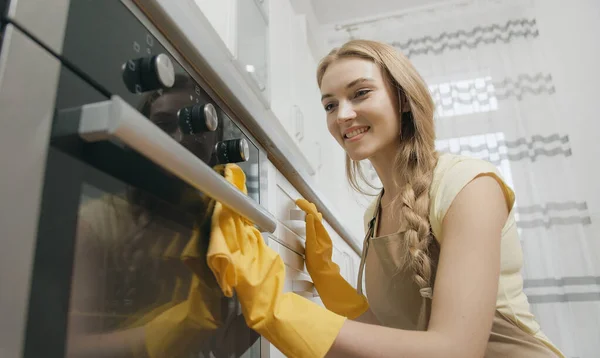 Niedliche blonde Hausfrau Reinigung Herd Oberfläche Stockfoto