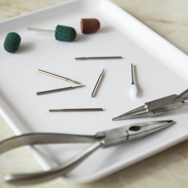 Medical instrument. Podoiogy burs, red and green caps, nippers on the white medical tray clipart