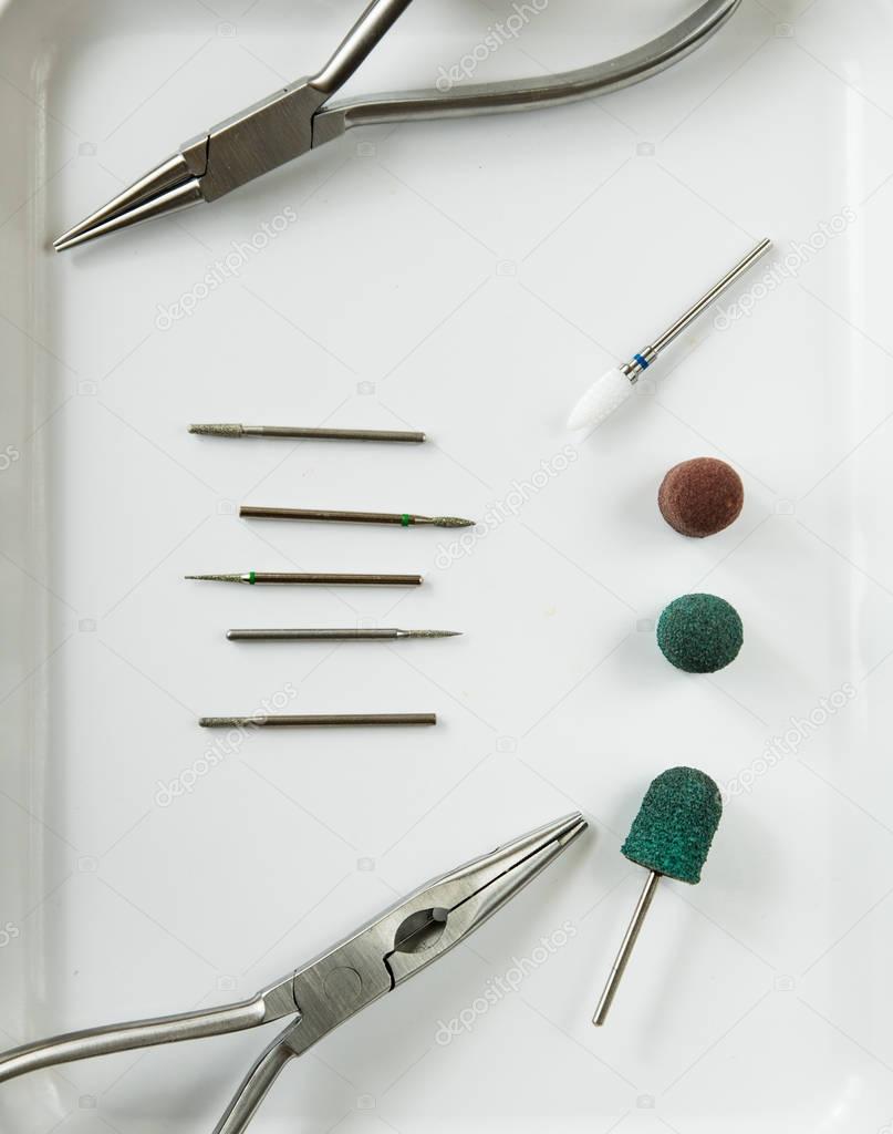 Medical burs, red and green caps, nippers on the white medical tray Podology equipment