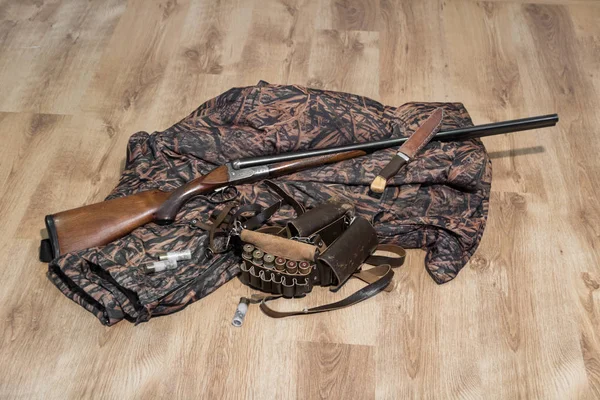 Old double-barreled shotgun, camouflage jacket, knife in scabbard, amunition belt and cartridges for shotgun — Stock Photo, Image