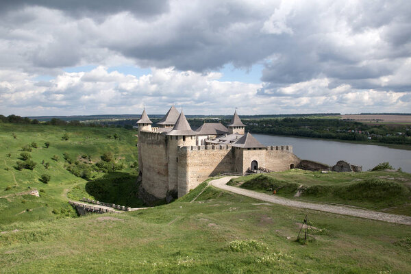 Вид на Хотинский средневековый замок на зеленом холме над рекой. Красивые серые облака
