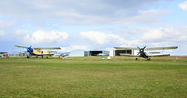 Aviones pequeños an-2 en el aeródromo, angares en el fondo — Foto de Stock