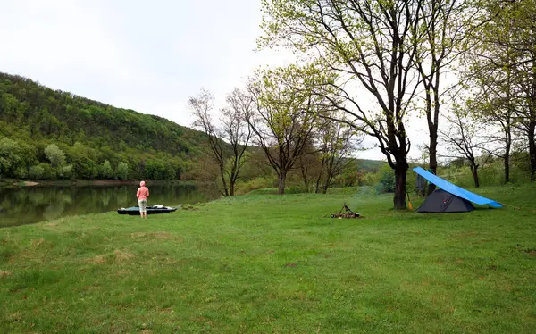 緑の空き地、キャンプ テント、川、カヤック、認識できない人 — ストック写真