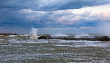 Mavi fırtınalı bulutlar, denizde fırtına, rıhtımda dalgalar kopuyor, kirli turuncu su