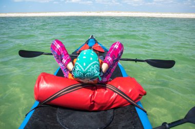 Sefer kanosundaki kız elinde kürekle mavi denizde dinleniyor.