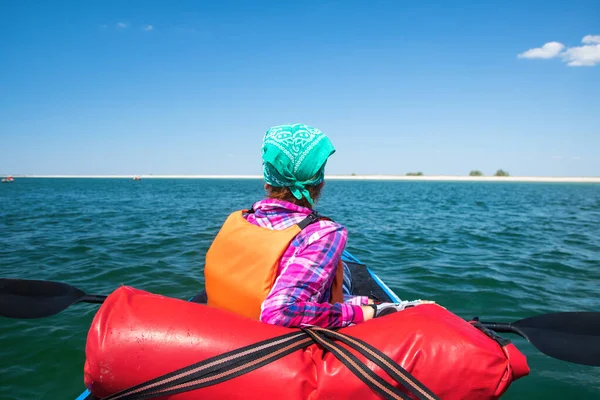 Girl in expedition kayak with a paddle in hands resting on the blue sea — Stock Photo, Image