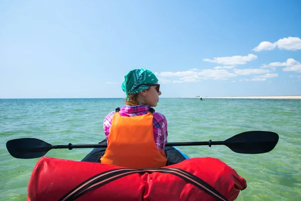 Girl in expedition kayak with a paddle in hands resting on the blue sea — Stock Photo, Image