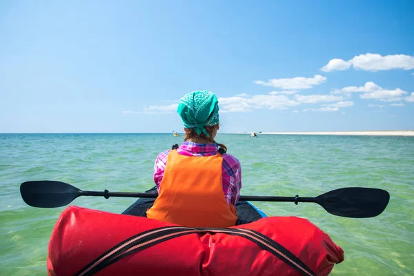 Girl in expedition kayak with a paddle in hands resting on the blue sea — Stock Photo, Image