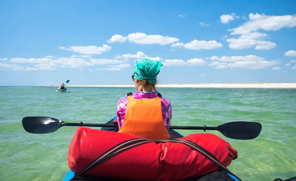 Chica en kayak expedición con una paleta en las manos descansando en el mar azul — Foto de Stock