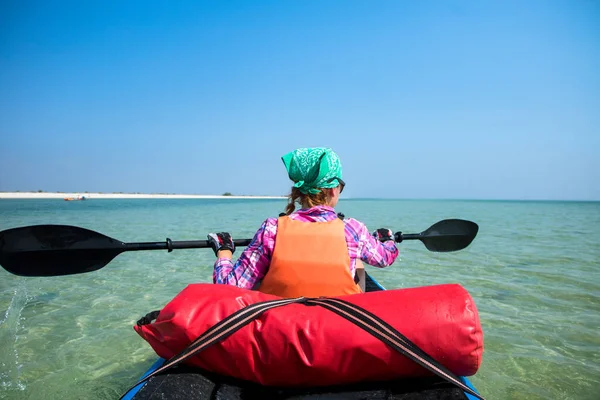 Mädchen im Expeditionskajak mit einem Paddel in der Hand auf dem blauen Meer — Stockfoto