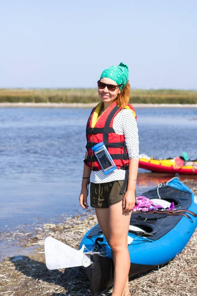 red-haired girl in red life vest prepearing for expedition on kayaks