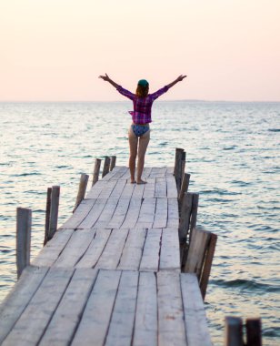 Gün batımında, sahilde, ahşap ranzadaki kızın silueti.