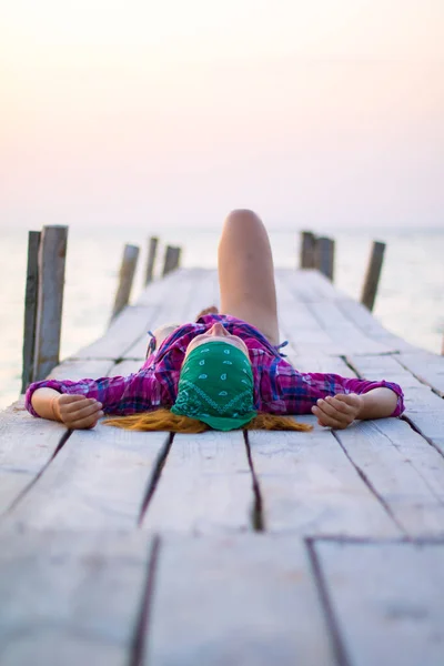 Meisje liggend op een oude houten pier en geniet van warme avond — Stockfoto