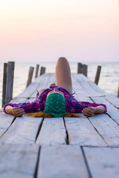 Meisje liggend op een oude houten pier en geniet van warme avond — Stockfoto