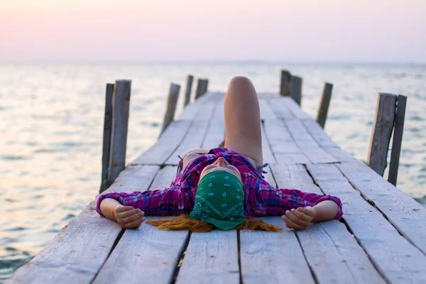 Meisje liggend op een oude houten pier en geniet van warme avond — Stockfoto