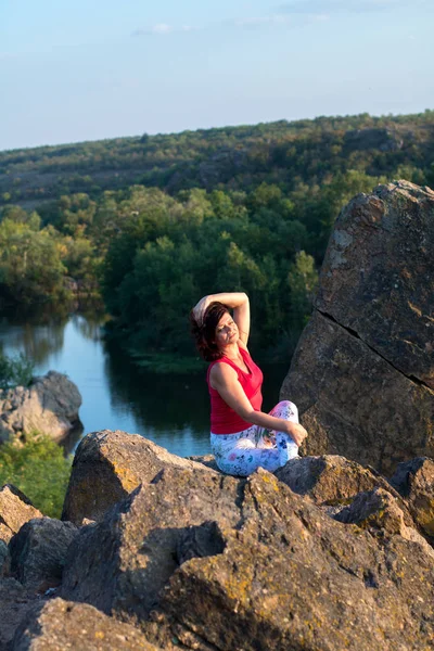 Adulte femme faire yoga asanas sur les rochers au-dessus de la rivière — Photo