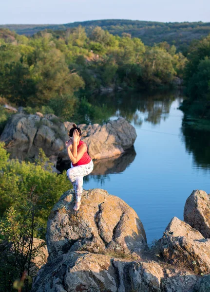 Adulte femme faire yoga asanas sur les rochers au-dessus de la rivière — Photo