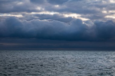 blue dark stormy clouds above the sea and ship on the horizon