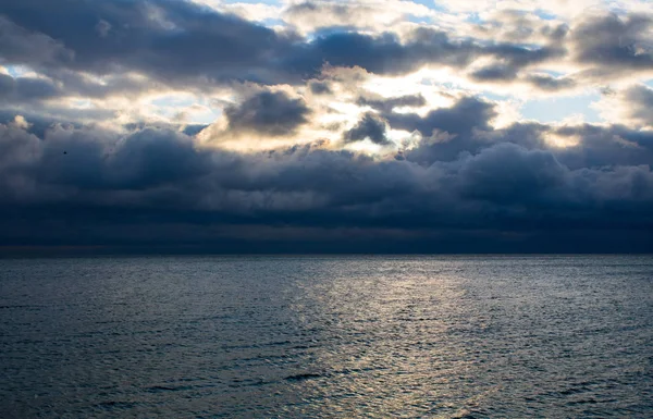 Blaue dunkle, stürmische Wolken über dem Meer, das Sonnenlicht bricht durch die Wolken — Stockfoto