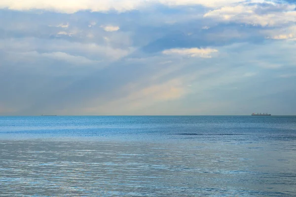 Ηλιαχτίδες στον ουρανό που λάμπει στη γαλάζια θάλασσα, πλοία στον ορίζοντα, χρόνος ηλιοβασιλέματος — Φωτογραφία Αρχείου