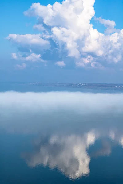 fog above the lake, clouds at sky and its reflection in the water