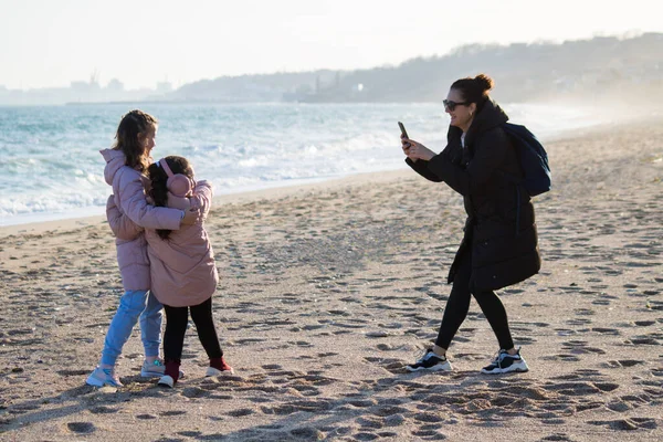 Młoda Matka Robiąca Zdjęcia Smartfonem Swoimi Córeczkami Plaży — Zdjęcie stockowe