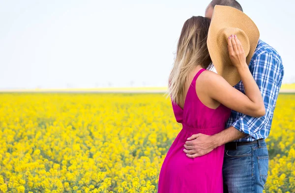 Sarı tarladaki genç beyaz çift öpüşüyor ve sarılıyorlar. Ekose gömlekli adam ve mor elbiseli kız.