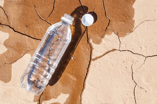 Пляшка води на сухому ґрунті — стокове фото