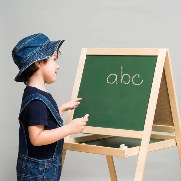 Petit garçon dessine de la craie sur un conseil scolaire — Photo