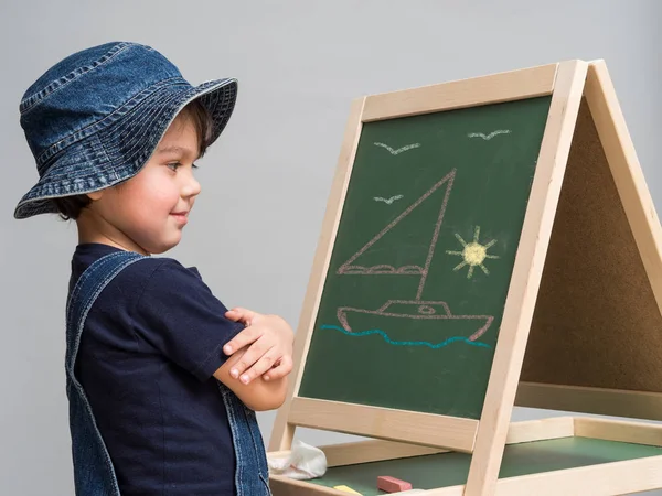 Kleiner Junge zeichnet Kreide auf Schultafel — Stockfoto
