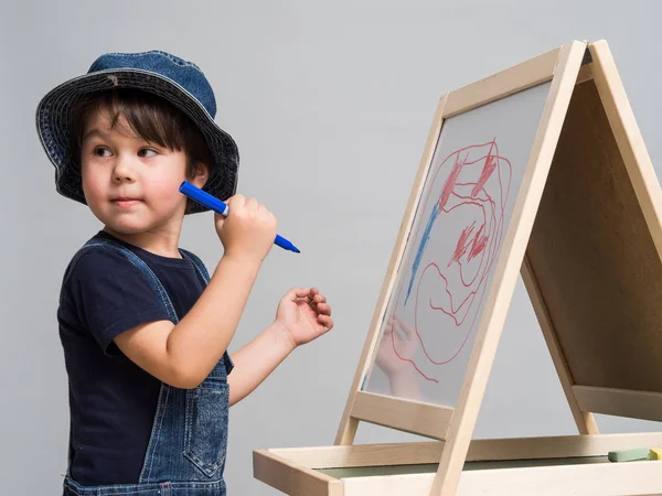 Pequeño niño dibuja tiza en una junta escolar — Foto de Stock