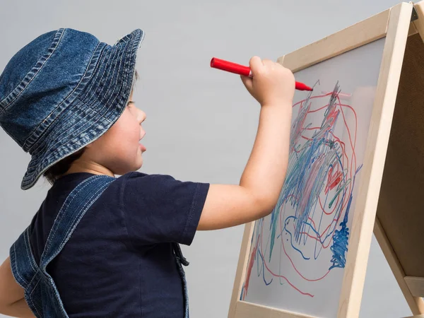 Pequeño niño dibuja tiza en una junta escolar — Foto de Stock