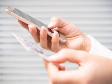 Bir kadın eli bir telefon ve bir banka kartı ile