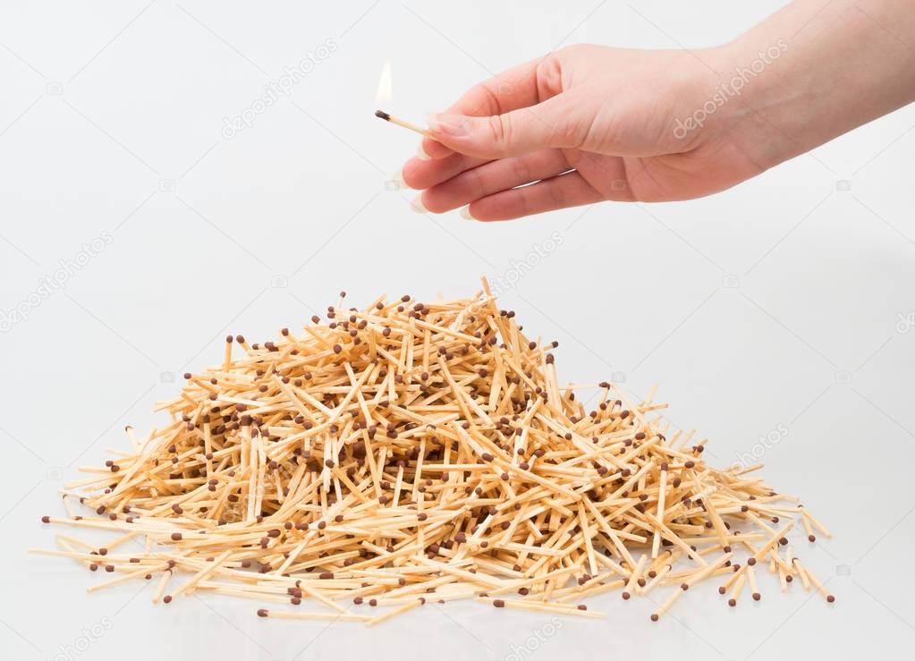 Bunch of matches threatened by another match.. A bunch of matches and a hand with a match