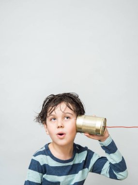 Küçük bir çocuk konserve kutusundan kulağına telefon bağlamış.