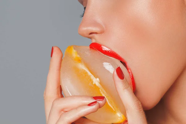Imagem de perto dos lábios vermelhos da mulher sexy com cubo de gelo. foto macro — Fotografia de Stock