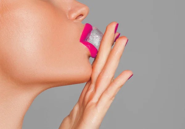 Un primo piano delle labbra rosse di una donna sexy con un cubetto di ghiaccio. macro foto Immagini Stock Royalty Free