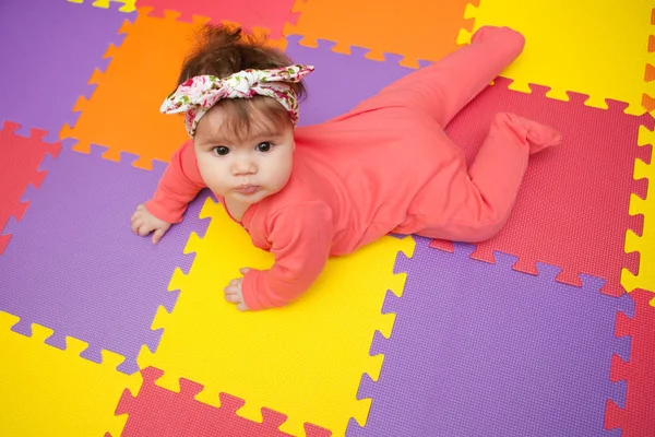 Rozkošný a stylově holčičku ležící na koberec puzzle — Stock fotografie