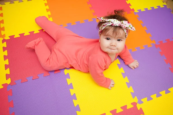 Adorable and stylish baby girl lying on a puzzle rug — Stock Photo, Image
