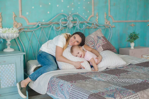 Ritratto al coperto di giovane bella donna godendo il suo tempo del mattino a casa con la sua bambina — Foto Stock