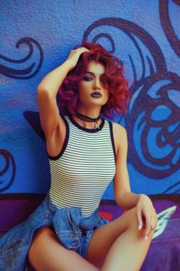 Grafiti duvara yakın poz kırmızı kıvırcık saç modeli ile moda ve Sexy kadın sokak görünümünü