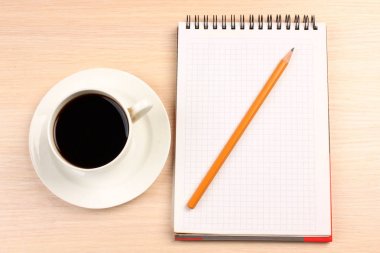 Bir fincan kahve ve masanın üstünde bir defter.