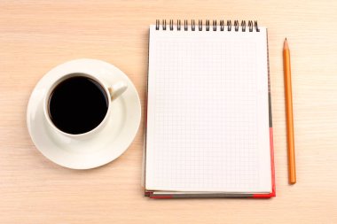 Bir fincan kahve ve masanın üstünde bir defter.